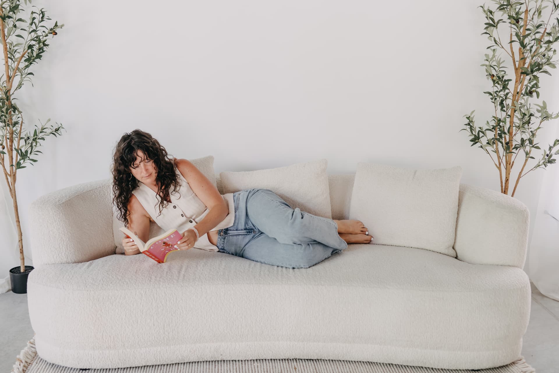 Shelby reading while relaxing on a cream sofa